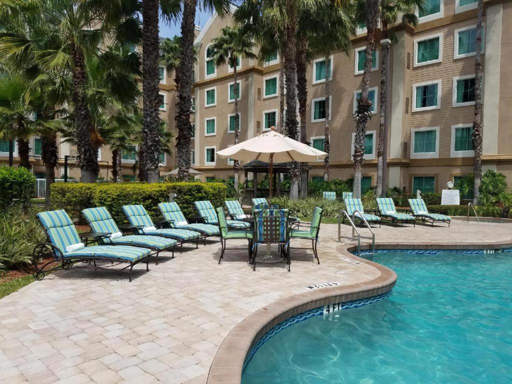 a pool with chairs and a table and an umbrella at Lake Buenavista Apartments close to Disney in Orlando