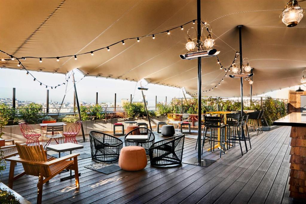 patio na dachu ze stołami, krzesłami i światłami w obiekcie Generator Paris w Paryżu