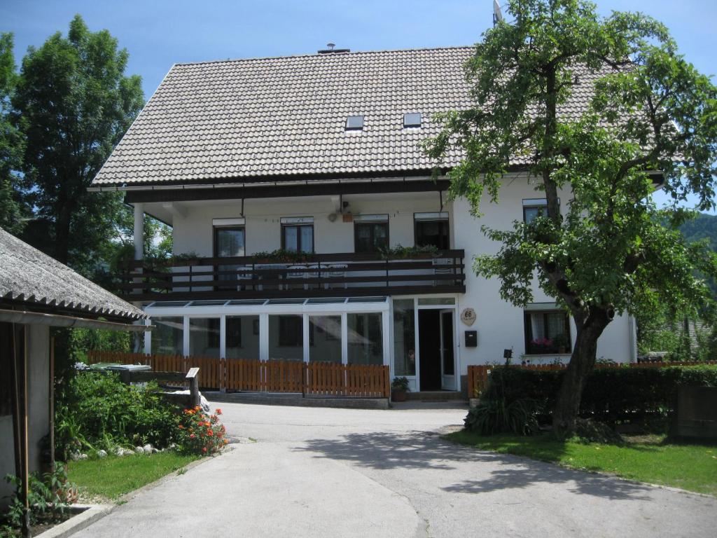 une grande maison blanche avec un arbre en face dans l'établissement Guest House Žnidar, à Bohinj