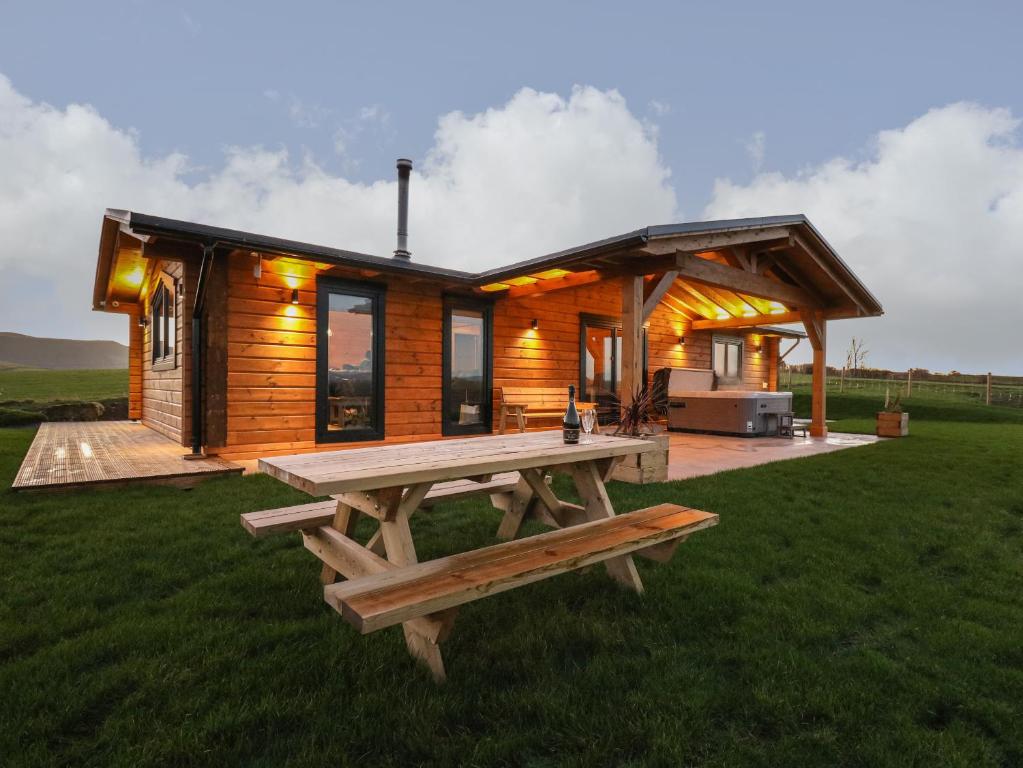 una cabaña de madera con una mesa de picnic delante de ella en Bacheiddon Log Cabin, en Machynlleth