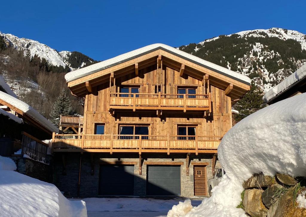 a wooden house with a balcony in the snow at Chalet Saint Maurice - piscine privée & jacuzzi in Champagny-en-Vanoise