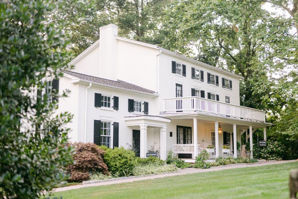 a white house with black windows and a yard at Fairville Inn in Chadds Ford