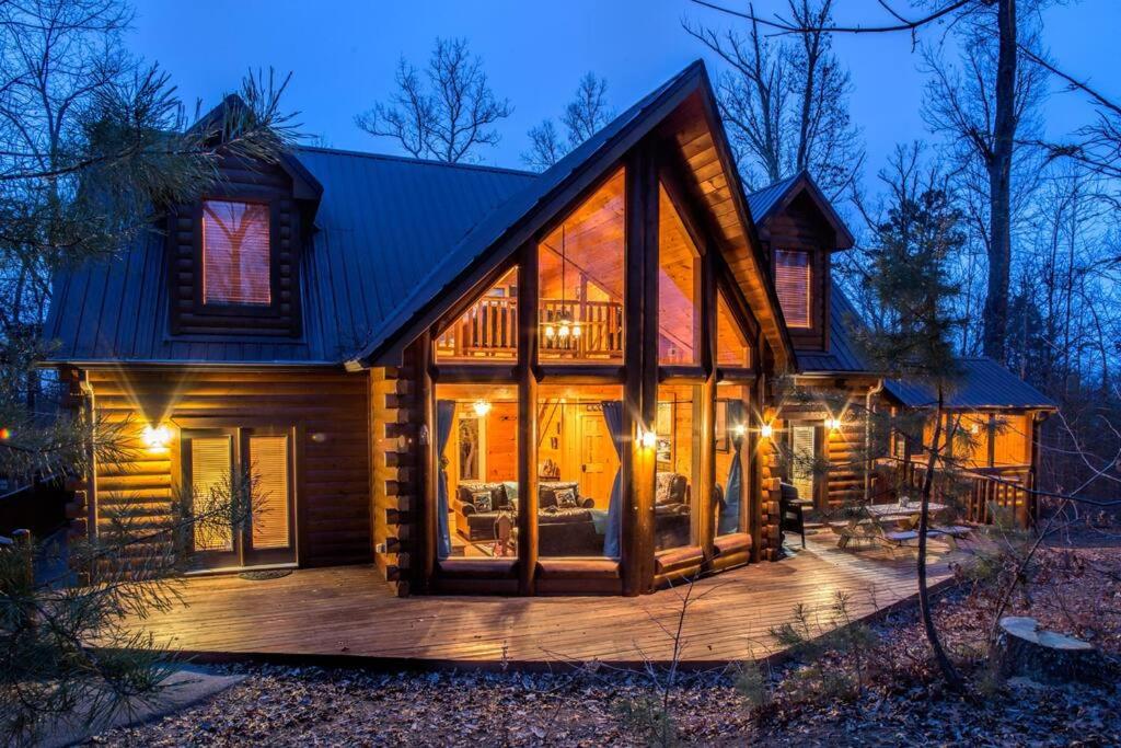 una casa de madera con una gran terraza por la noche en Kozy Bear Kabin en Sevierville