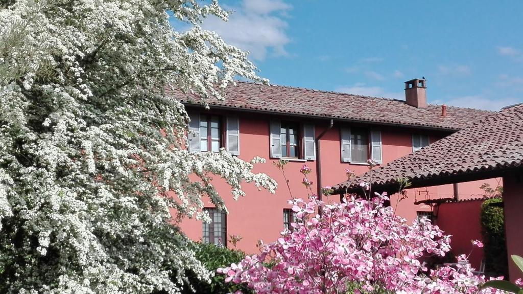 una casa rosa con flores blancas delante en La Foresteria dei Baldi, en Pavia