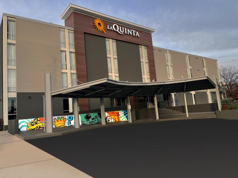 a building with a sun sign on the front of it at La Quinta Inn & Suites by Wyndham Tulsa Downtown - Route 66 in Tulsa