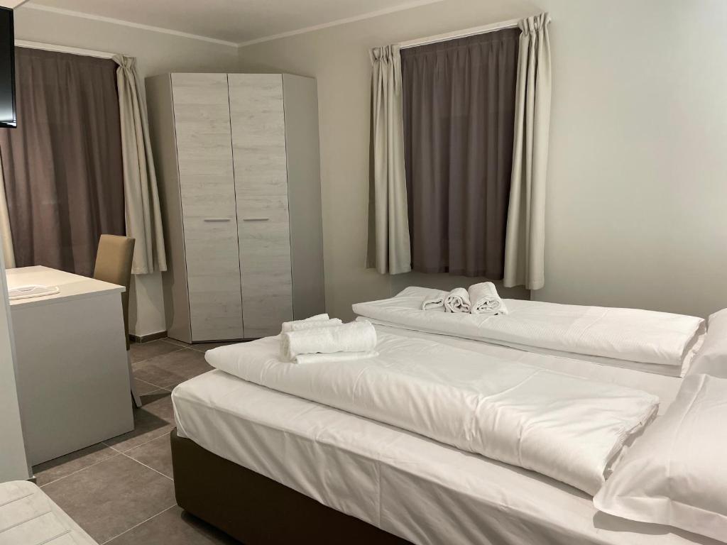 two beds in a hotel room with white sheets at Antica locanda al Gelso in Monfalcone