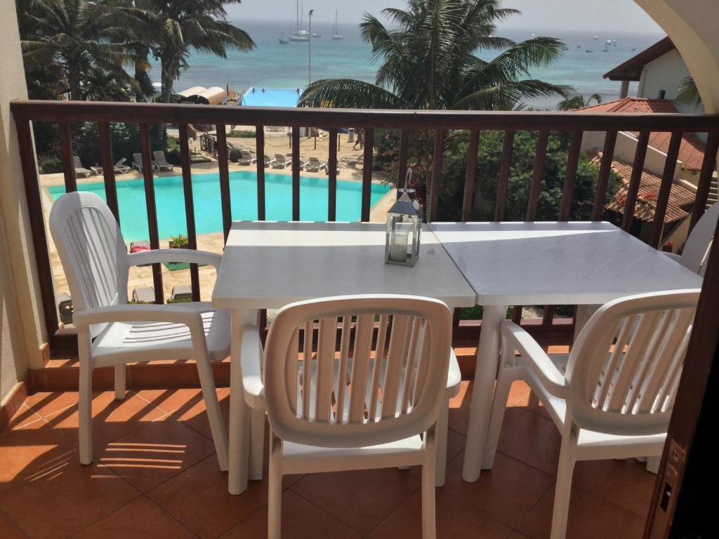 a white table and chairs on a balcony with a pool at Apt71 Porto Antigo 2 in Santa Maria