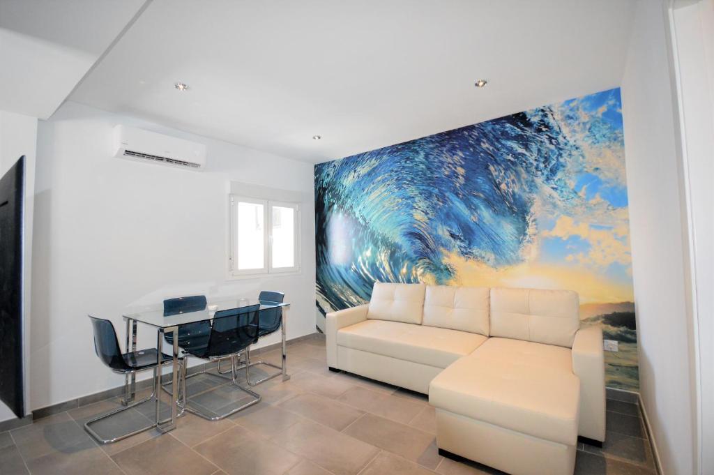 a living room with a white couch and a painting at Apartamento La Ola in Conil de la Frontera