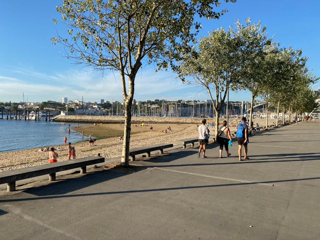 un grupo de personas caminando por una playa con bancos en Porto Douro Marina, en Vila Nova de Gaia