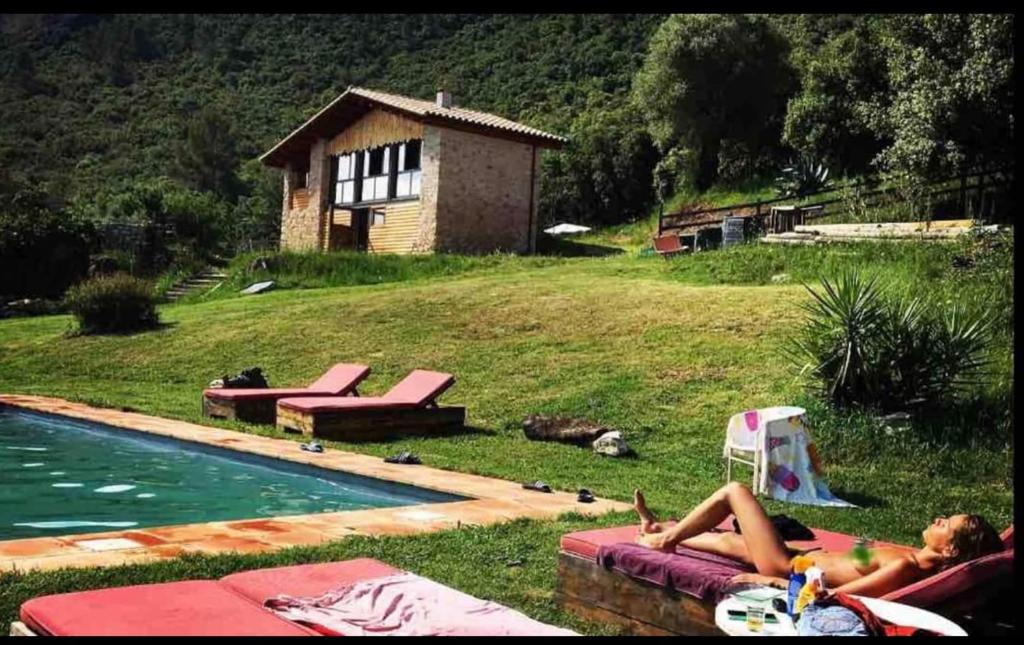 a couple of people laying in the grass near a swimming pool at La Granera in Girona