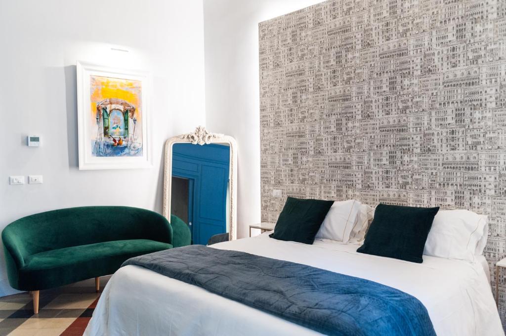 a bedroom with a bed and a green chair at CATARINA SUITES - CENTRO STORICO in Catania