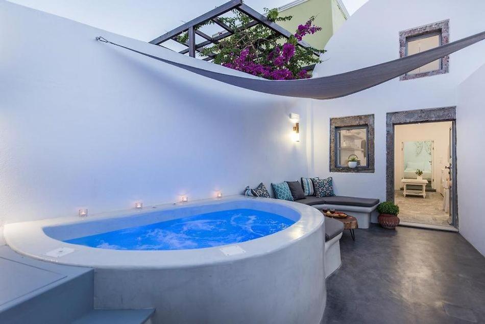 een groot blauw bad in een kamer met een bank bij Angels Villa Santorini in Megalokhori
