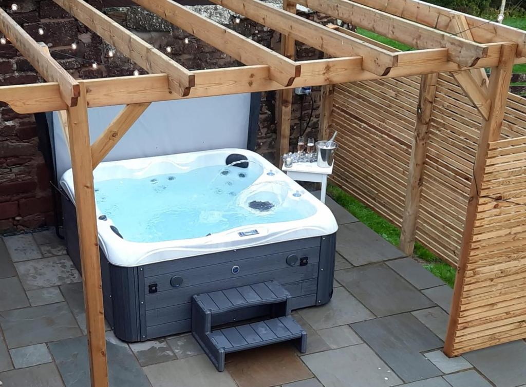 a hot tub in a backyard with a pergola at Old Post Office - Hot Tub, Real Fire, Cumbrian Lakes Coastal Cottage in St Bees