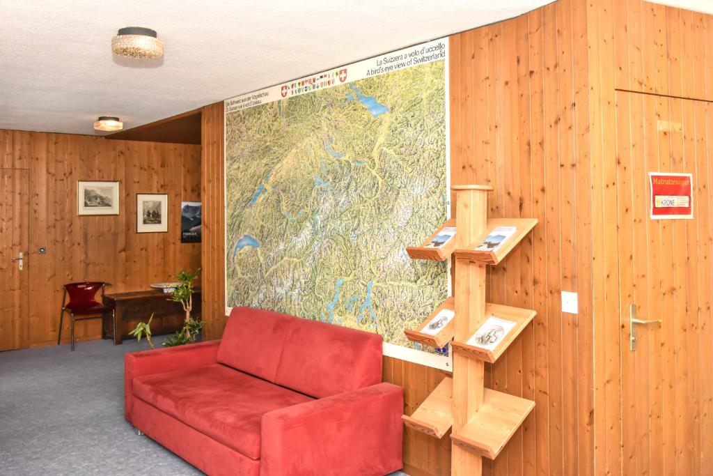 a room with a red couch and a map at Hotel Krone in Attinghausen