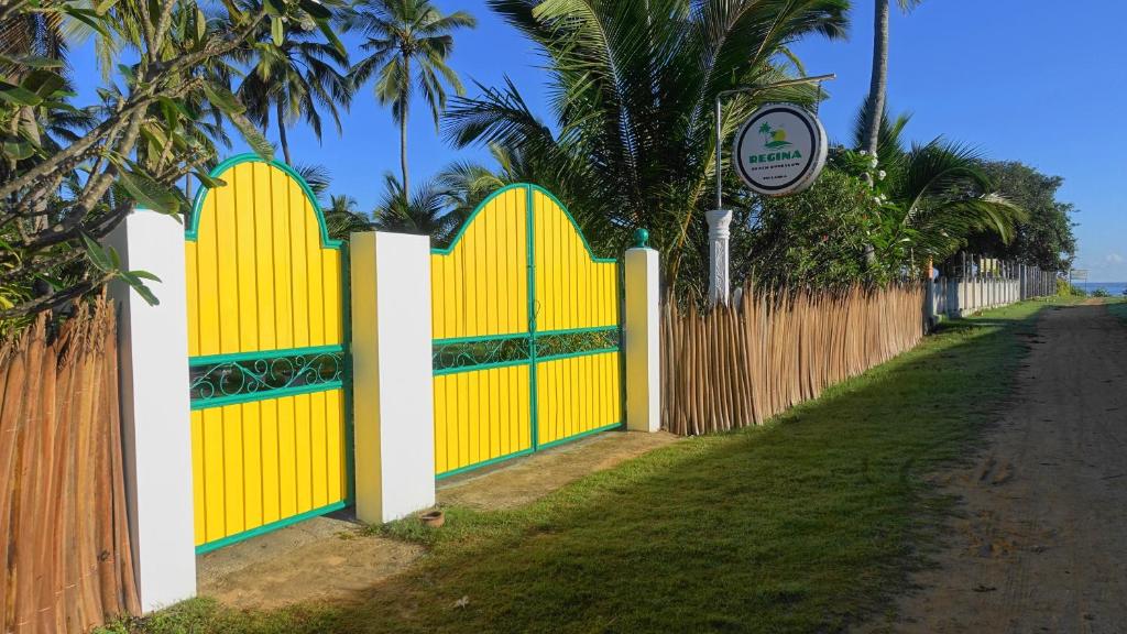 uma cerca com portões amarelos na berma de uma estrada em Regina Beach Bungalow em Trincomalee