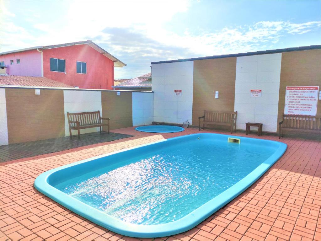 una gran piscina en un patio con 2 bancos en Disponivel Virada - Estúdios e suítes com piscina, ar, wifi e estacionamento 6X no cartão sem juros, en Porto Belo