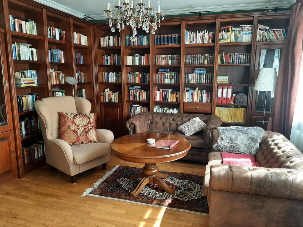 ein Wohnzimmer mit 2 Stühlen, einem Tisch und Bücherregalen in der Unterkunft Ferienwohnung Burgzauber in Wiltingen