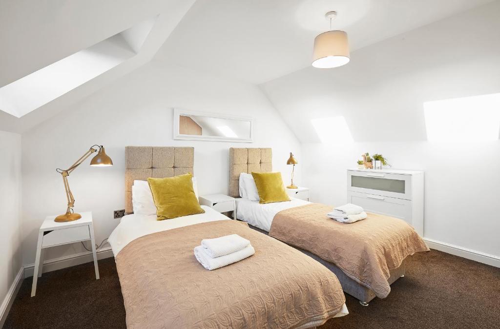 two beds in a room with white walls and yellow pillows at Ambler Thorn Lodge in Queensbury
