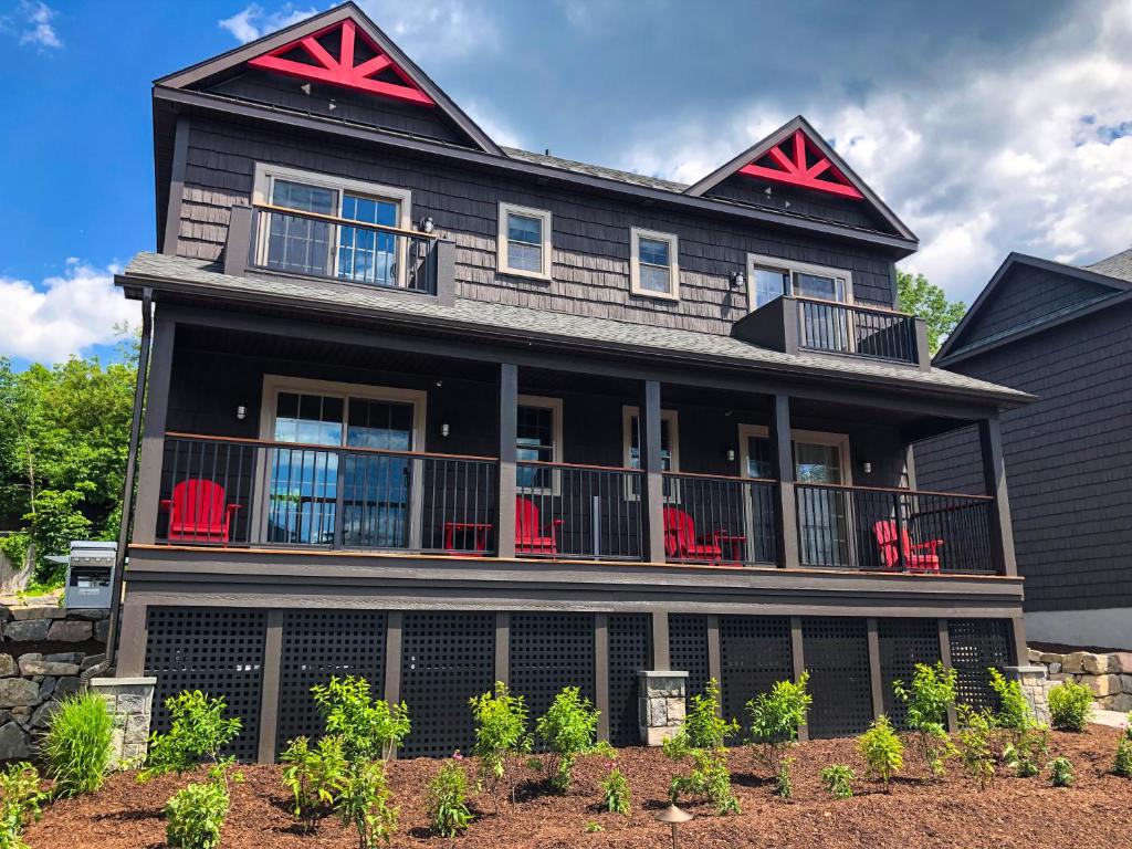 a black house with red chairs in front of it at Lakeside Lodging in Lake George