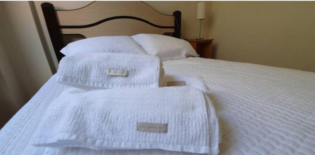 a white bed with white sheets and pillows at Local Ideal - Lindo apartamento em Teresópolis in Teresópolis