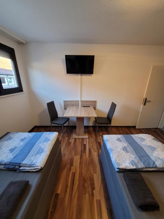 um quarto com duas camas e uma mesa e uma televisão em City Apartment KL em Kaiserslautern