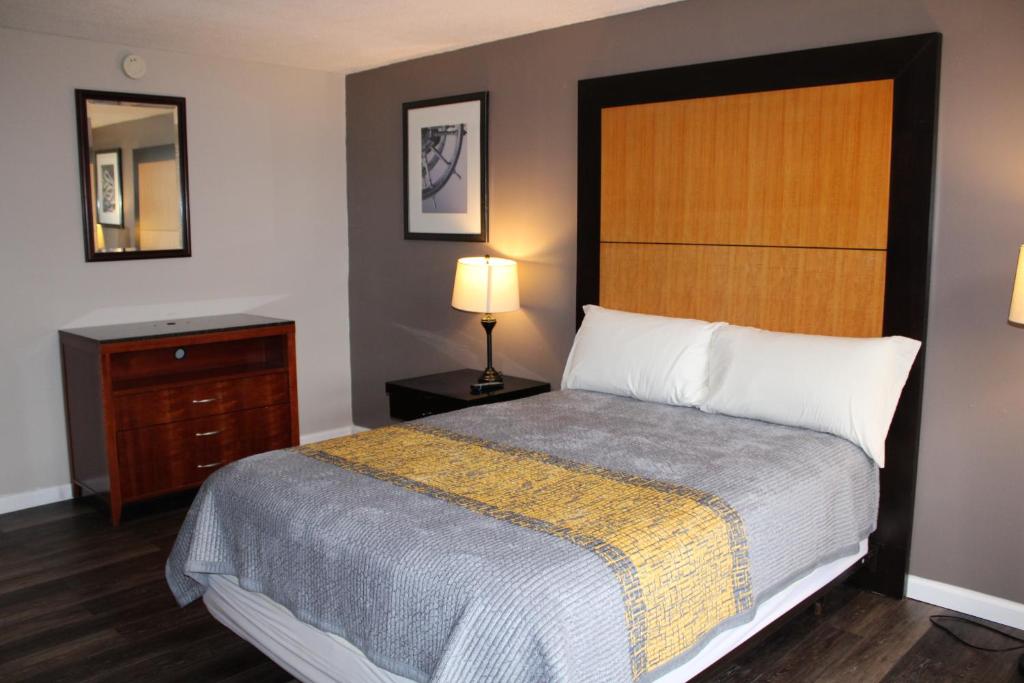 - une chambre avec un lit, une commode et un miroir dans l'établissement APM Inn & Suites, à Martinsburg