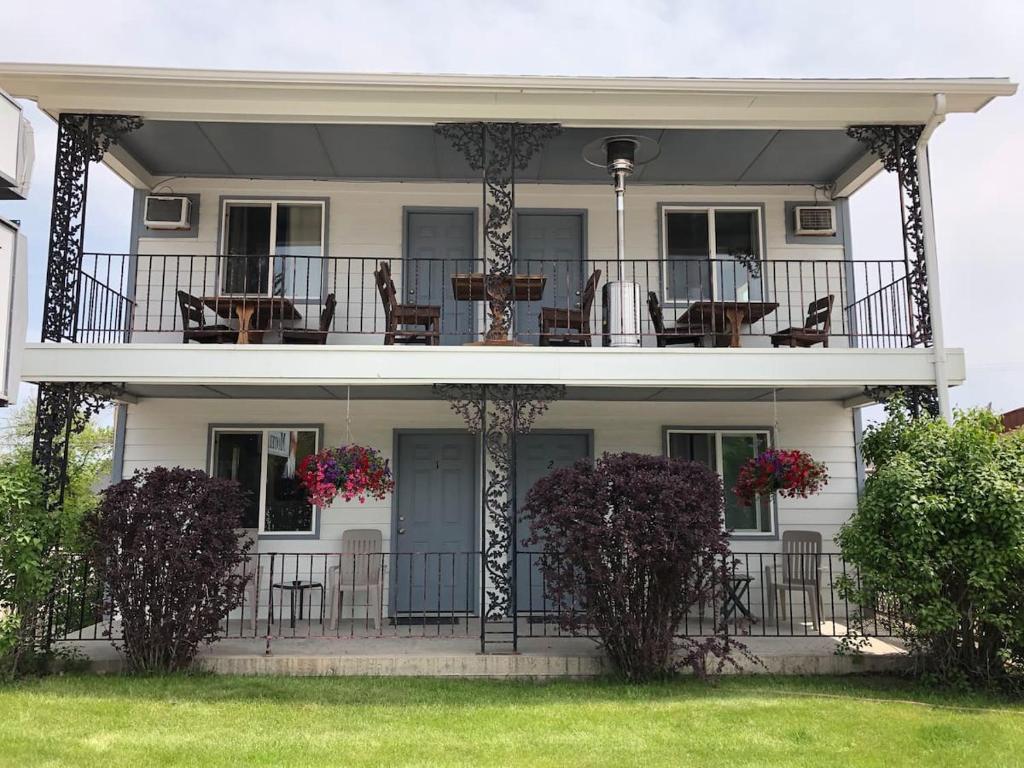 a white house with chairs and tables on a balcony at Mansion House Motel in Buffalo