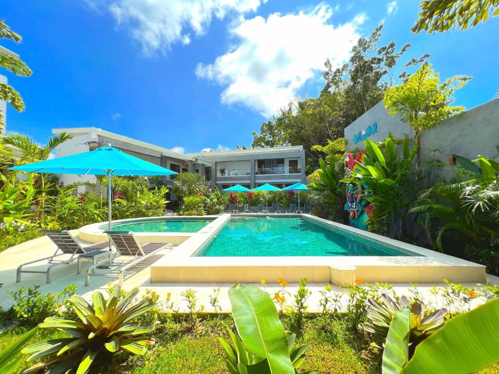 a pool with chairs and umbrellas in front of a house at Hotel Naoz in Manuel Antonio