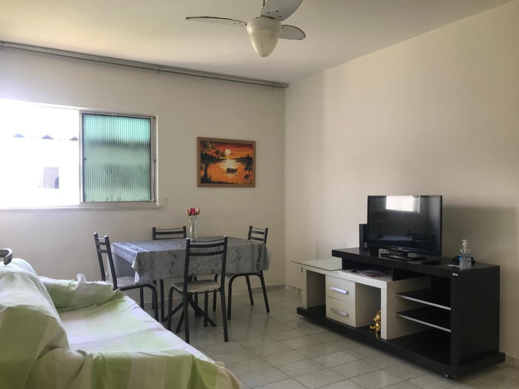 ein Wohnzimmer mit einem Bett und einem Tisch mit einem TV in der Unterkunft Mar Azul Condomínio in Aracaju
