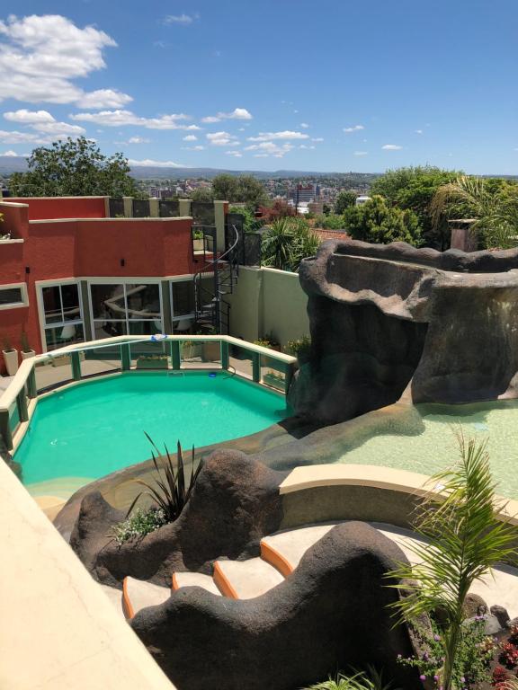 a swimming pool with a rock wall next to a building at Los Naranjos Apart Hotel in Villa Carlos Paz