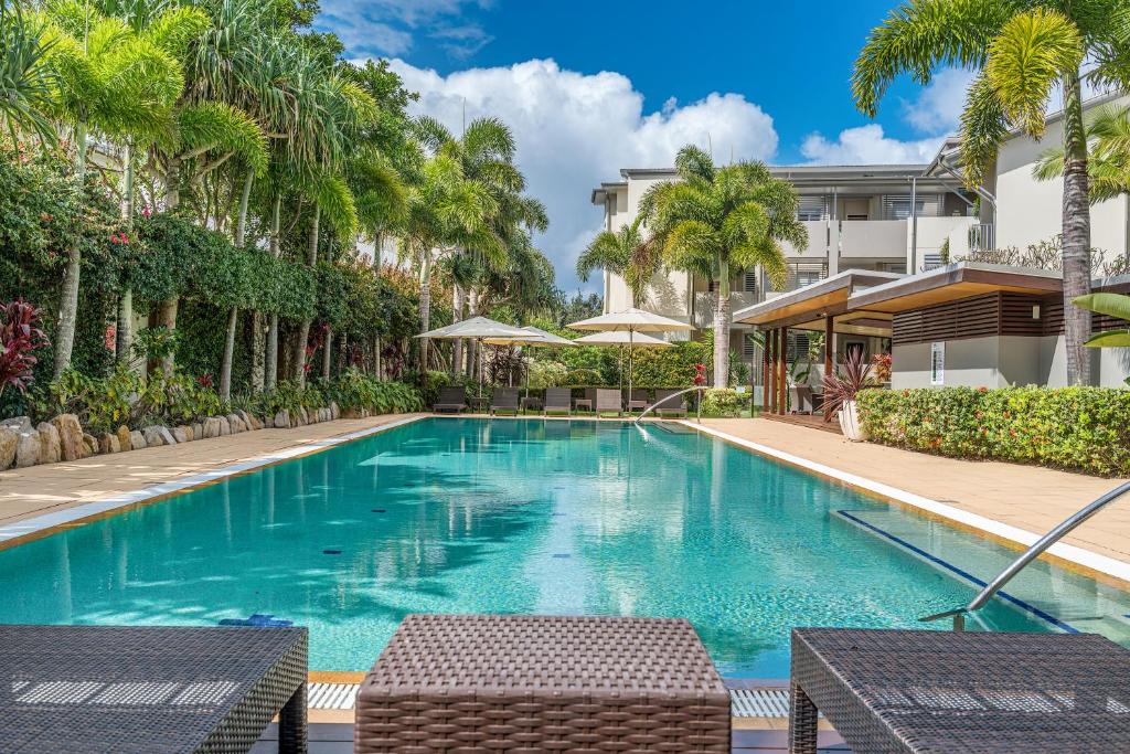 a swimming pool with palm trees and a building at Salt Beach Luxury Apartments by Kingscliff Accommodation in Kingscliff