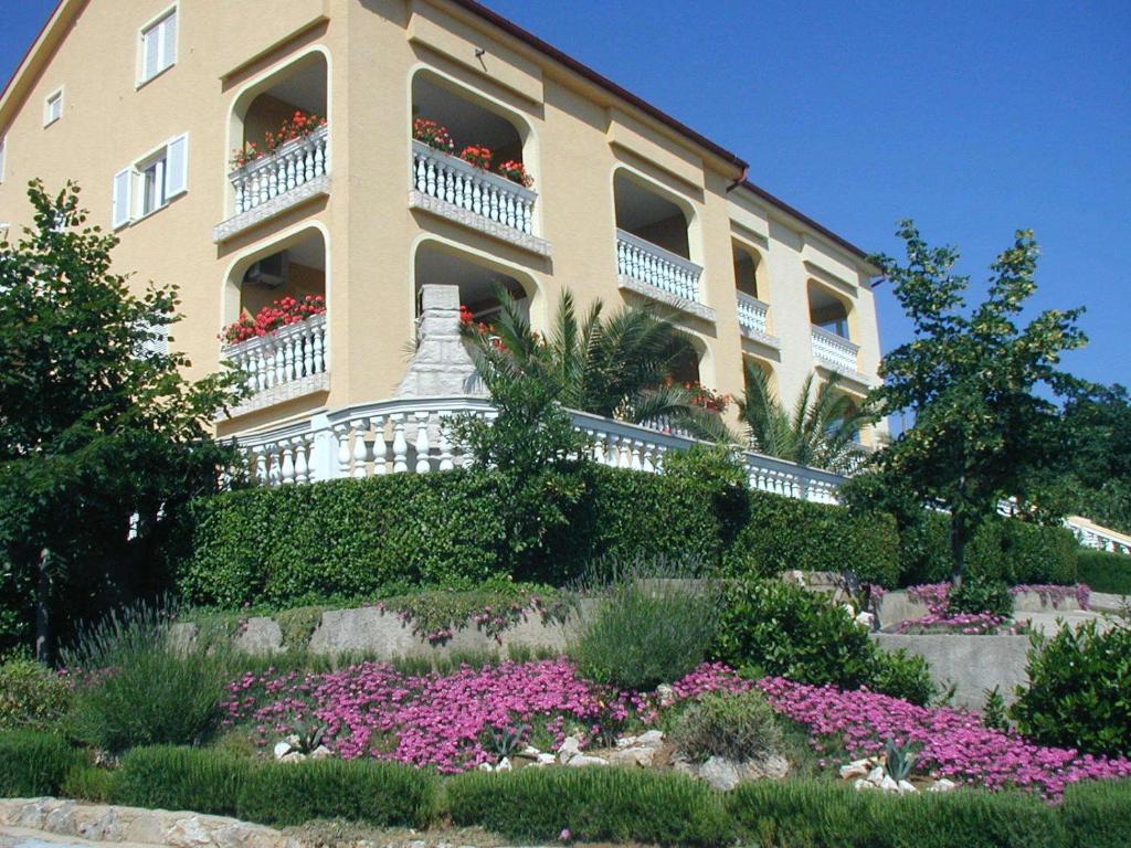 ein Gebäude mit Balkonen und Blumen im Garten in der Unterkunft Apartments 3 Palms in Crikvenica