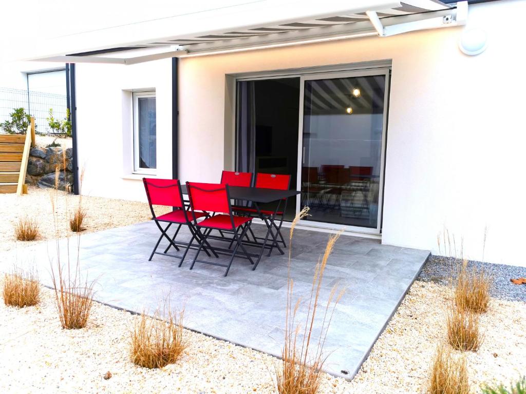 eine Terrasse mit roten Stühlen und einem Tisch vor einem Haus in der Unterkunft Les Jacinthes in Saint-Jean-de-Monts