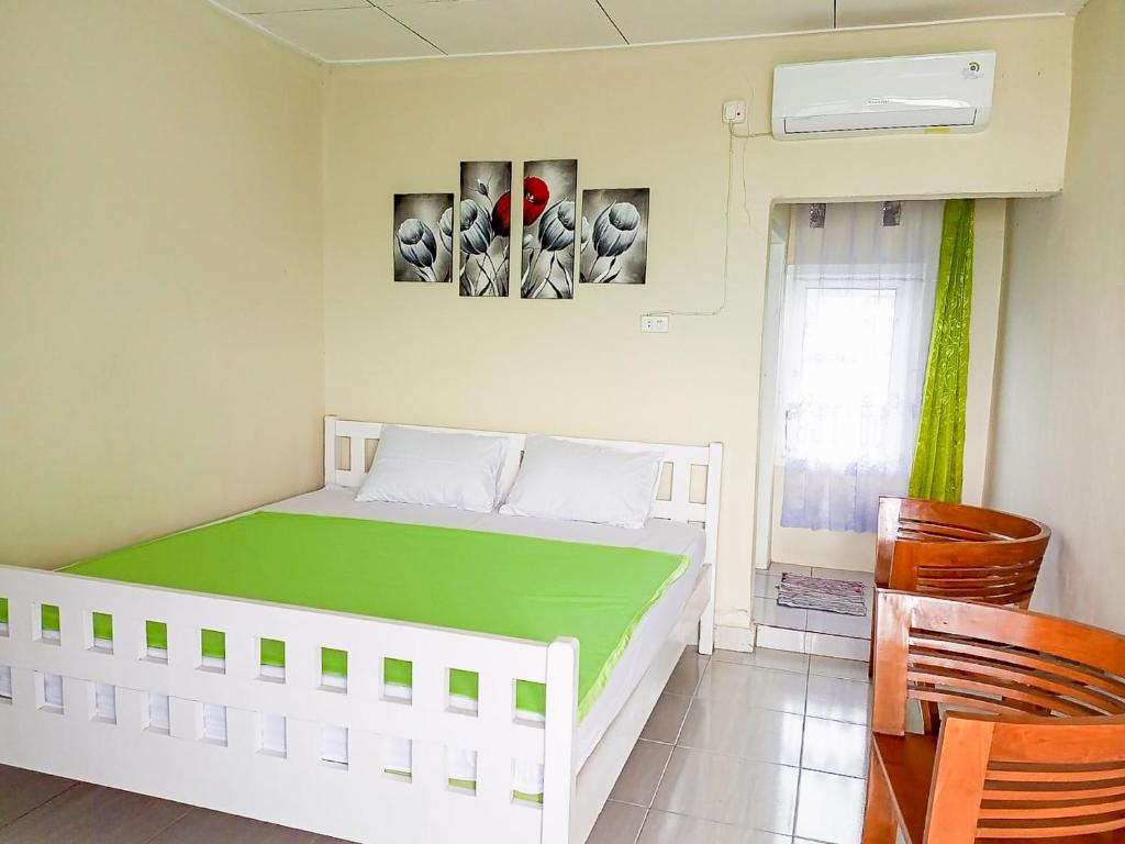 Homestay Sakinah Belitung RedPartner في Tanjungbinga: غرفة نوم بسرير ابيض مع بطانيه خضراء