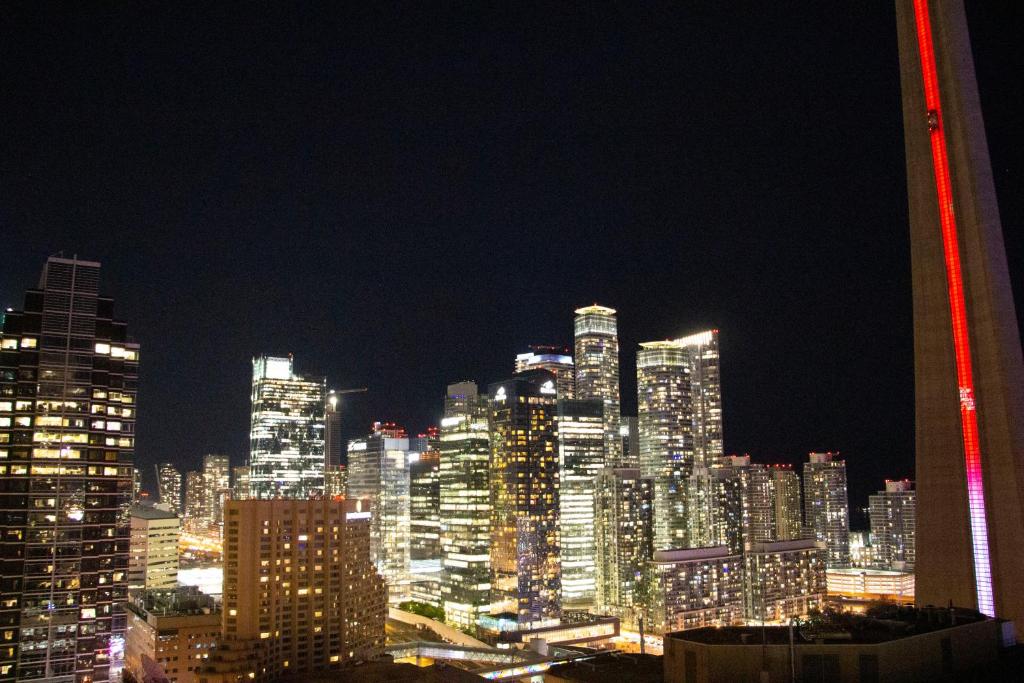 - une vue nocturne sur une grande ville avec un grand bâtiment dans l'établissement Downtown High-rise Condo- CN Tower View, à Toronto
