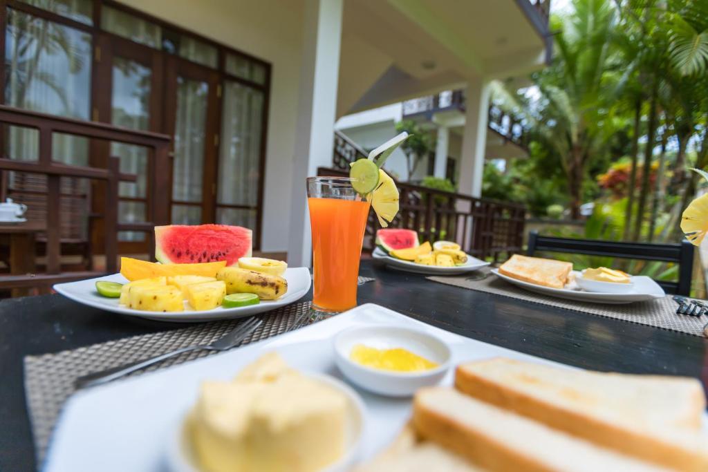 una tavola con piatti di cibo e un bicchiere di succo d'arancia di Shine Wave Turtle Beach a Tangalle