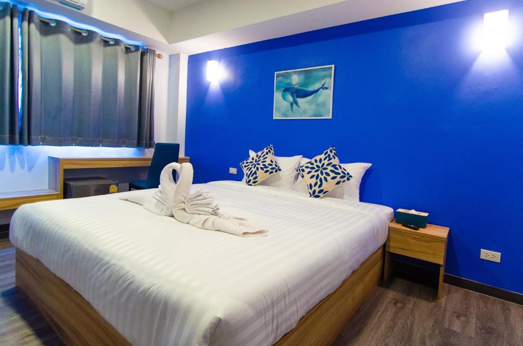 um quarto com uma cama grande e uma parede azul em Bleu Marine Sattahip Hotel em Ban Nong Srah