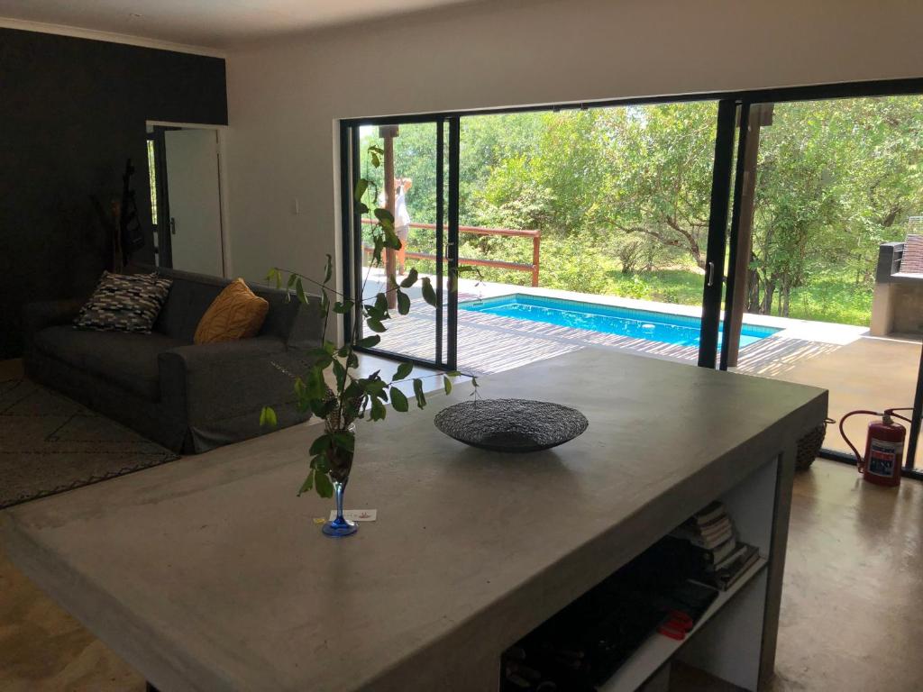 uma sala de estar com uma mesa e uma piscina em Kruger Willows em Marloth Park