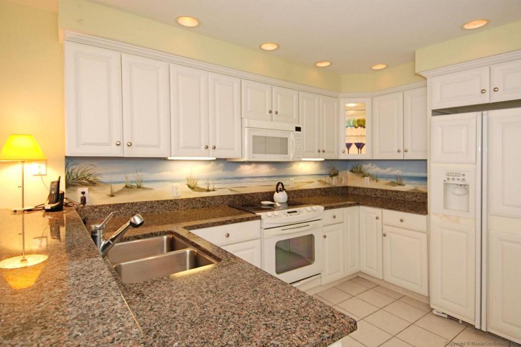 a kitchen with white cabinets and a sink at Adagio 402 in Ocean City