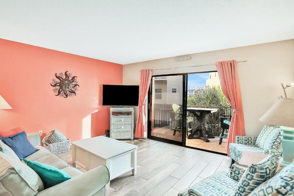 a living room with a couch and chairs and a tv at The Beach Escape in Clearwater Beach