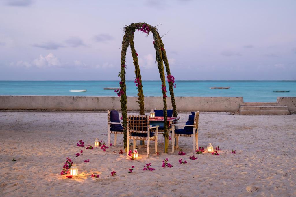 a table and chairs on the beach with candles at Nur Beach Hotel in Jambiani