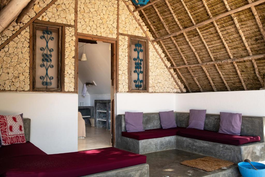 a living room with two couches and purple pillows at Nur Beach Hotel in Jambiani