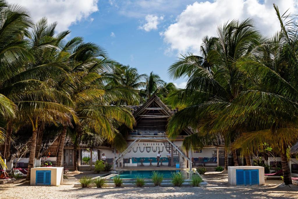 un bâtiment avec des palmiers en face de celui-ci dans l'établissement Nur Beach Hotel, à Jambiani