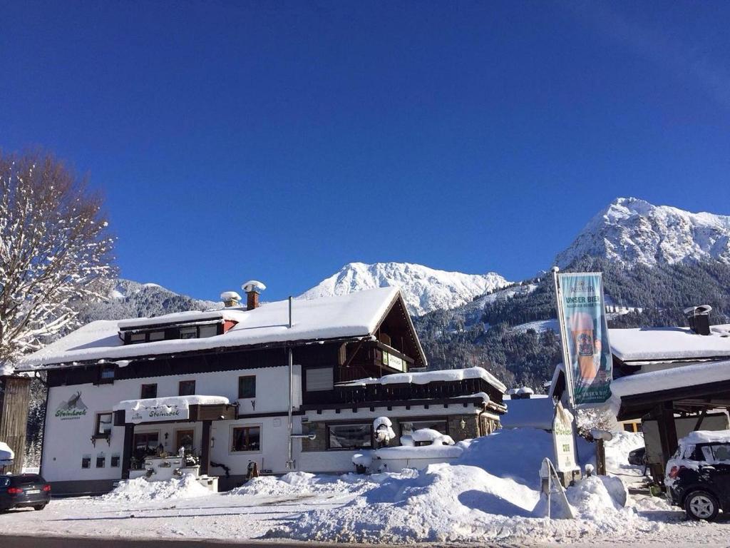 un edificio cubierto de nieve con montañas en el fondo en Steinbock Bed & Breakfast, en Fischen