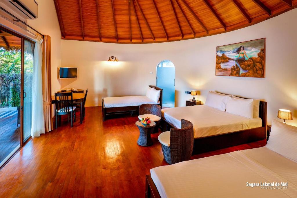a hotel room with two beds and a table and chairs at The Blue Lagoon Resort Kalpitiya in Kalpitiya