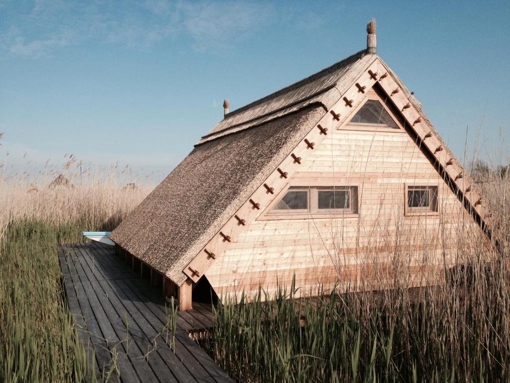 ein Haus mit einem Strohdach auf einer Promenade in der Unterkunft Pfahlbau Rust/Neusiedlersee in Rust