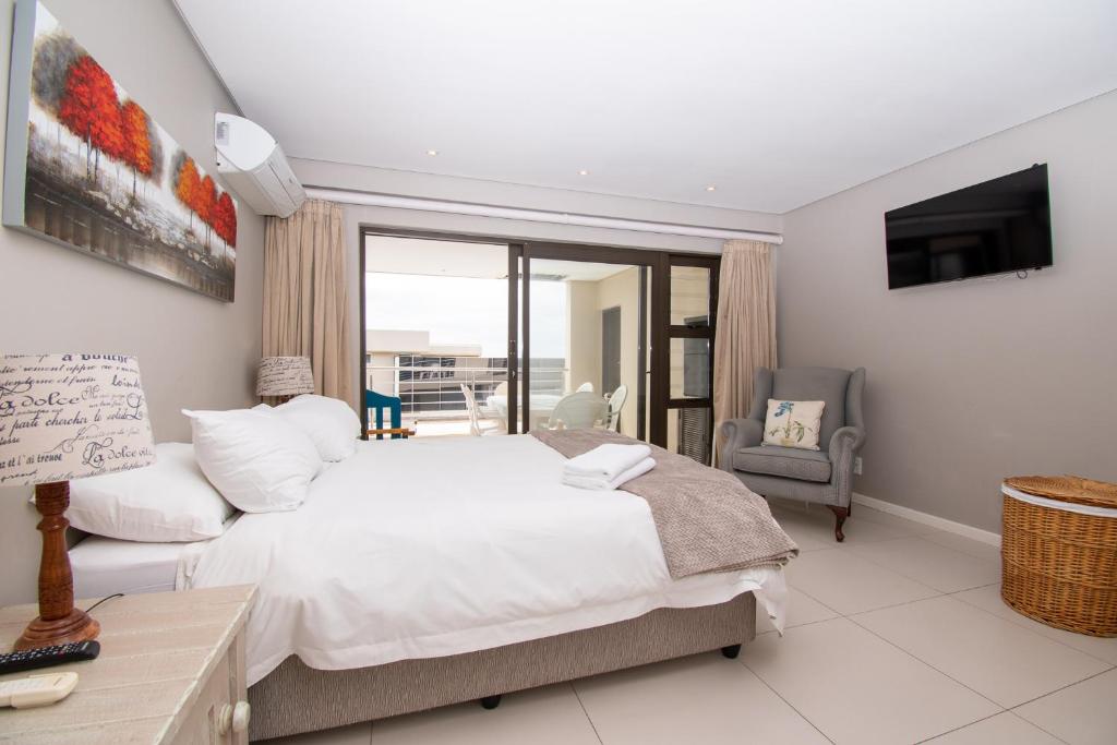 a bedroom with a large white bed and a television at 26 Bronze Beach Umhlanga Rocks in Durban
