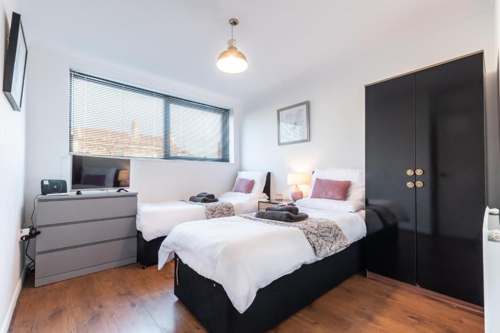 a bedroom with two beds and a window at BEST PRICE!! - Contractor Heaven! 4 Singles beds or 2 King Size, Southsea Apartment- FREE PARKING, SMART TVS in Portsmouth