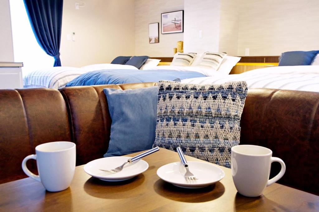 two cups on a table with two beds at TOMMY CONDOMINIUM WAKASA 601 in Naha