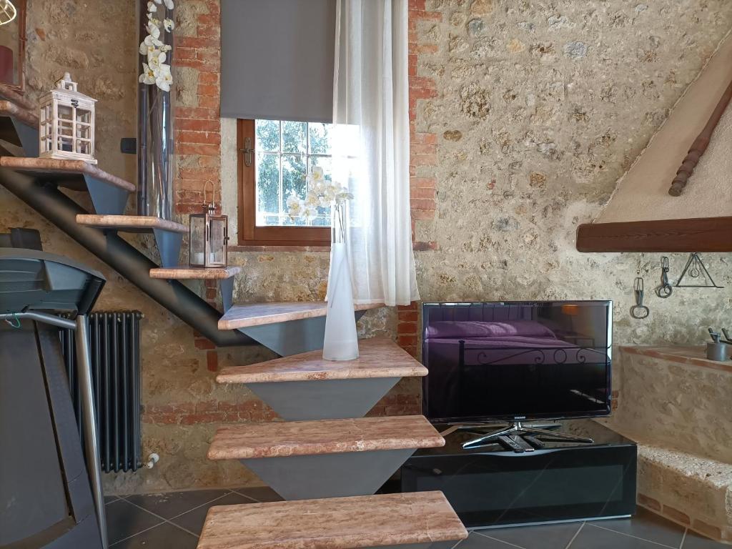 Pokój z klatką schodową, telewizorem i wazą w obiekcie La Limonaia Country House w mieście Monteriggioni
